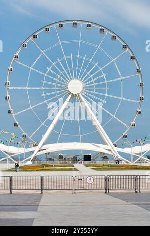 Bakou, Azerbaïdjan - 4 mai 2024 : vue de la grande roue Baku Eye, située à côté du centre commercial Deniz. La roue est en arrière-plan avec peu de gens marchant au premier plan Banque D'Images