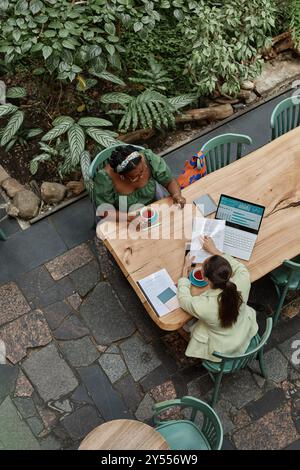 Plan vertical de haut en bas de deux femmes d'affaires prospères discutant de documents dans un café Banque D'Images