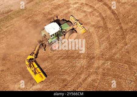 Themenfoto : Landwirtschaft. Ein Landwirt faehrt mit seinem Traktor ueber einn abgeerntetes Maisfeld und verjunegt den Boden mit der Schaelfraese,Schlepper, Traktorspuren. *** Photo thématique Agriculture Un agriculteur conduit son tracteur sur un champ de maïs récolté et désherbe le sol avec la houe rotative, tracteur, tracteurs chenilles Banque D'Images