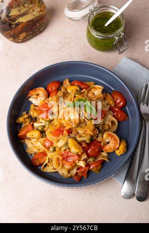 Nouilles aux crevettes, moules, tomates, oignons et câpres. Les pâtes sont servies avec de l'huile d'olive et de la sauce pesto. Cuisine méditerranéenne traditionnelle maison Banque D'Images