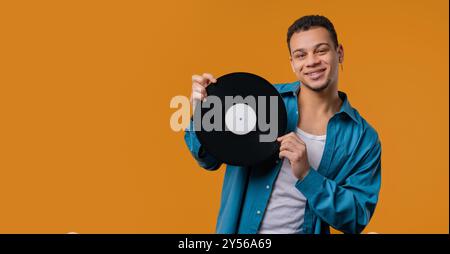 Homme élégant avec disque vinyle sur jaune. Hobby, mélomane, collection Banque D'Images