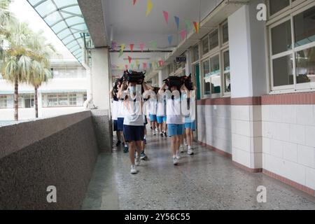 Des élèves du secondaire du premier cycle ont mis leur cartable sur la tête et sont allés à l'extérieur pour participer à l'exercice sismique annuel à Taipei sur Septembe Banque D'Images
