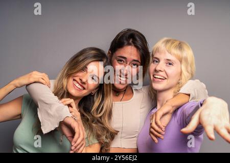 Diverses jeunes femmes amies embrassant et riant ensemble sur un fond neutre. Portrait authentique mettant en valeur une amitié authentique, inclusivit Banque D'Images