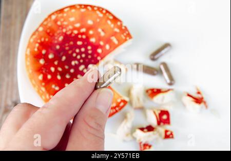 Image conceptuelle de mouche agarique Amanita muscaria pilules médicinales capsules. Mouillez les champignons agariques et les pilules de supplément sur fond blanc, à l'intérieur. Banque D'Images