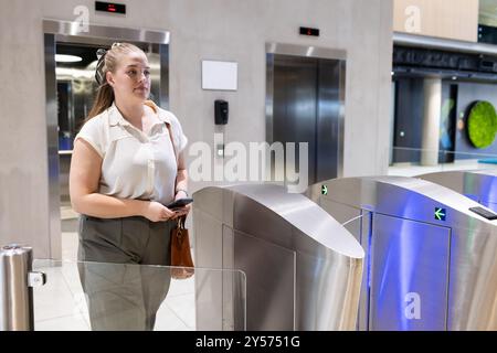 Entrée dans l'immeuble de bureaux, femme utilisant la carte d'accès au tourniquet de sécurité Banque D'Images