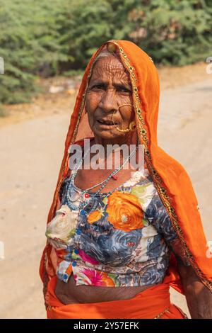 Tilora, Ajmer, Rajasthan, Inde. 9 novembre 2022. Femme avec un foulard orange et un grand anneau de nez en or. Banque D'Images