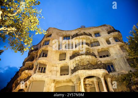 Explorez l'architecture étonnante de la Casa Mila de Gaudi, magnifiquement éclairée lors d'une nuit à Barcelone, mettant en valeur son design unique sur le Paseo de Banque D'Images