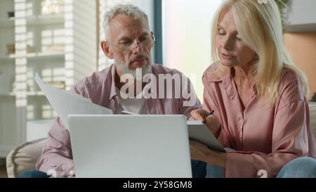 Sérieux senior senior retraité vieux couple caucasien femme femme mari homme documents de travail documents financiers utilisent un ordinateur portable pc. Femme homme parler Banque D'Images