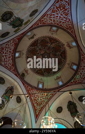 Vue détaillée du dôme d'une mosquée avec calligraphie islamique et motifs ornementaux. Les motifs complexes et les couleurs vives soulignent le traditionnel Banque D'Images