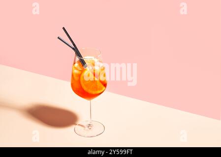 Aperol Spritz cocktail en verre avec des tranches orange sur fond de pêche rose, espace copie, lumière dure à la mode. Été délicieuse boisson Aperol Spritz Aper Banque D'Images