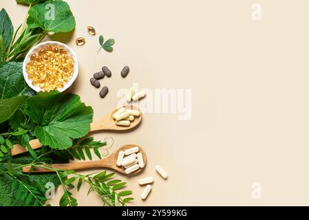 Vitamines naturelles, suppléments à base de plantes et feuilles vertes sur fond beige, vue de dessus, espace de copie. Diverses capsules et pilules biologiques végétaliennes. Banque D'Images