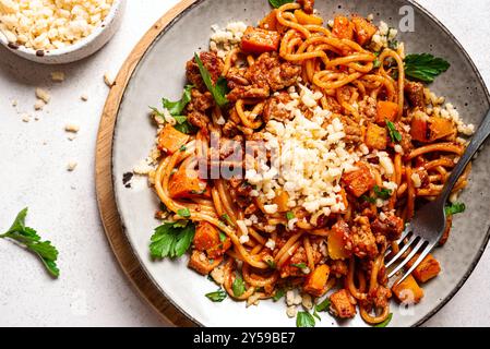 Pâtes spaghettis bolognaises à la citrouille et au bœuf avec parmesan râpé. Spaghetti maison citrouille et pâtes à la viande sur assiette gros plan. Confort saisonnier Banque D'Images