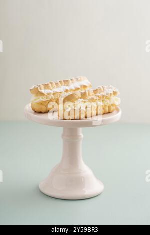 Eclairs avec garniture de crème au beurre sur un stand à gâteau Banque D'Images