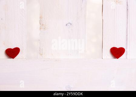 Mignons petits coeurs rouges, affichés un à gauche et un à droite d'une clôture en bois blanc. Un concept d'amour, rupture, romance, saint valentin Banque D'Images