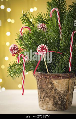 Gâteau rouge POPS avec ruban dans le bouquet de décoration de Noël avec des cannes de bonbons et un peu d'épicéa. Très faible profondeur de champ et lumières de Noël dans le BA Banque D'Images