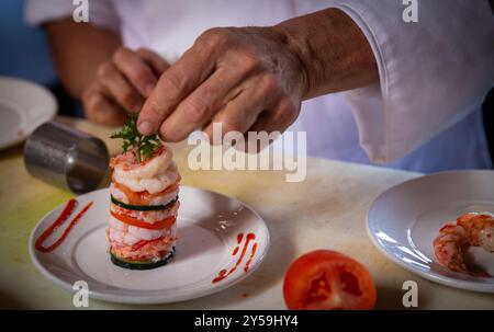 Chef cuisant une tour de fruits de mer avec concombres et sirachi Banque D'Images