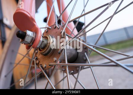 Détails complexes d'un moyeu de roue de vélo vintage et des rayons, mettant en valeur les composants métalliques sur un fond extérieur flou. Banque D'Images