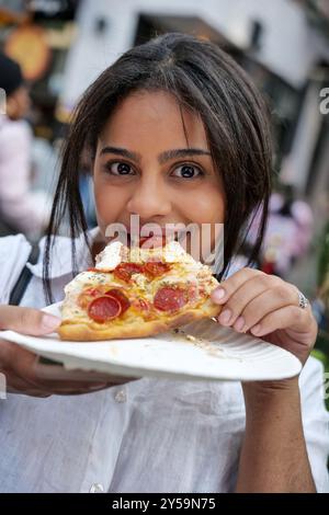 New York, New York, États-Unis. 19 septembre 2024. La fête célèbre la vie de San Gennaro de Naples qui était évêque de Bénévent Italie et a été martyrisé en 305 AD. Le festival Little Italy est connu pour sa cuisine italienne comme la pizza, les saucisses, les cannolis, les zeppoles et plus encore. Tout ce qui est italien. Anne Burrell, célèbre chef cuisinière, était le grand maréchal. Manger une tranche au festin. (Crédit image : © Milo Hess/ZUMA Press Wire) USAGE ÉDITORIAL SEULEMENT! Non destiné à UN USAGE commercial ! Banque D'Images