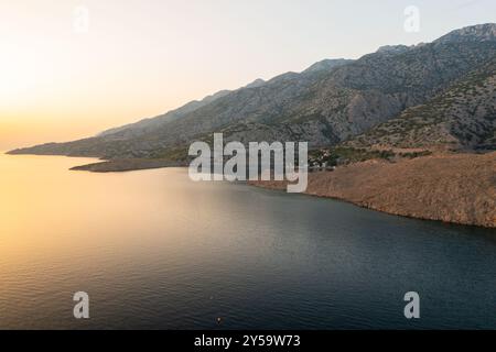 Village côtier parmi les montagnes escarpées entourées par la mer. De petites maisons avec des toits de tuiles rouges et une végétation luxuriante créent une scène pittoresque Banque D'Images