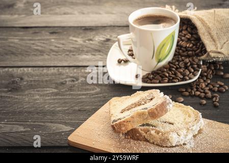 Deux tranches de pound cake sur une trancheuse de bois, recouvert de sucre en poudre sur une table en bois avec des grains de café et tasse en arrière-plan Banque D'Images