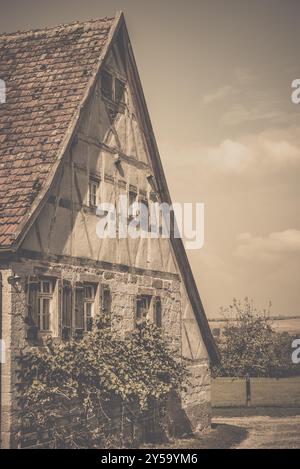 Image de style rétro d'une ancienne maison allemande à l'architecture traditionnelle, toit à pignon, mur à colombages pour le grenier et mur de pierre, volet en bois Banque D'Images