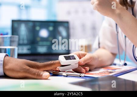 Médecin spécialiste plaçant un oxymètre sur le doigt du patient pour mesurer les niveaux d'oxygène et la saturation, surveiller le pouls et les signes vitaux. Consultations médicales professionnelles sur l'assurance maladie. Banque D'Images