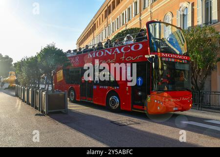 Vue en contre-jour avec des lumières éclairantes d'un bus touristique à arrêts multiples rempli de personnes au départ du Musée océanographique par une journée ensoleillée d'hiver, Monaco Banque D'Images