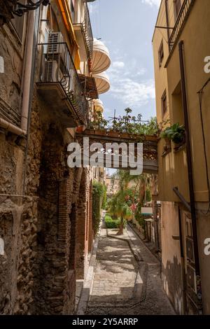 Taormina, Italie - 19 juin 2024 : une rue étroite dans la vieille ville. Vertical. Banque D'Images