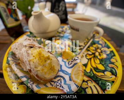 Catane, Italie - 20 mai 2024 : pâtisserie sicilienne célèbre et traditionnelle appelée canolli sur une plaque décorée jaune. Banque D'Images