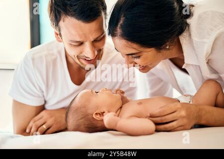 Parents, heureux et bébé pour les soins, le lien et le développement avec le soutien, l'amour et se détendre à la maison. Nouveau-né, famille et sourire pour la connexion, la croissance et Banque D'Images