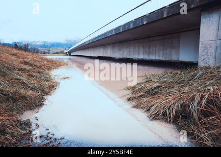 Berge inondée sous un grand pont en béton, niveau d'eau élevé, temps couvert, concept de catastrophe naturelle Banque D'Images