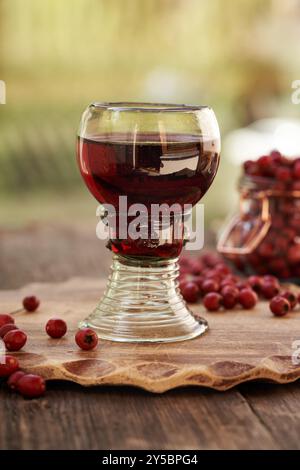 Une tasse de verre de vin médicinal préparé à partir de baies d'aubépine fraîches, à l'extérieur Banque D'Images