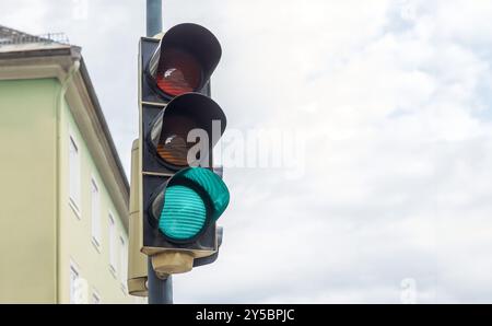 Feu de circulation vert dans un cadre urbain, signalant vers l'avant sous un ciel dégagé, assurant la sécurité de la rue et le transport en douceur à une intersection, cit Banque D'Images