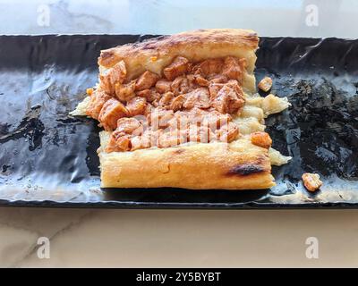 Restes, de Stipska Pastrmajlija, plat traditionnel macédonien : concept Hunger Games – pâte avec tranches de viande de poulet sur assiette en céramique noire Banque D'Images