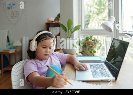 Fille utilisant l'ordinateur portable pour faire ses devoirs Banque D'Images