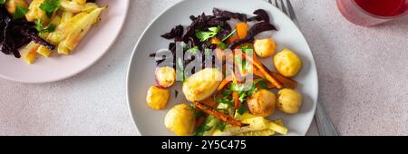 Savourez un repas sain de légumes cuits au four comme les pommes de terre, les courgettes, les carottes et les betteraves, accompagné de fruits frais et de compote de cerises, parfait pour un hea Banque D'Images