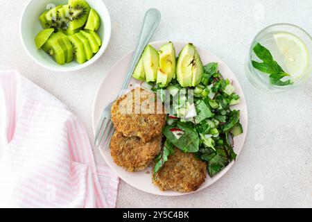 Côtelettes de quinoa et salade mixte avec avocat et radis, kiwi et eau au citron, délicieux petits déjeuners copieux, assiette végétalienne Banque D'Images