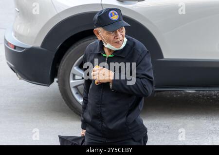 SAMUT PRAKAN, THAÏLANDE, 08 février 2023, un vieil homme en uniforme des services de sécurité marche dans une rue de l'après-midi Banque D'Images