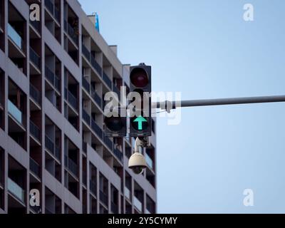 Un feu de circulation avec un feu vert est sur une rue devant un bâtiment. Une caméra de sécurité CCTV est montée sur le feu tricolore. Photo de haute qualité Banque D'Images