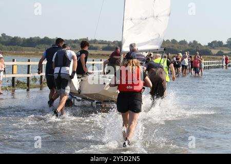 Île de Mersea, Royaume-Uni. 21 septembre 2024. Le tour annuel de la course de l'île a eu lieu autour de l'île de Mersea dans l'Essex aujourd'hui. Des voiliers de toutes sortes participent à l'événement. Les équipages doivent transporter leurs bateaux à travers la Strood, la seule route sur et hors de l'île qui inonde lors de marées exceptionnellement hautes. Credit:Eastern Views/Alamy Live News Banque D'Images