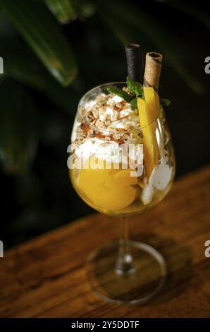 Mangue biologique et fruit de la passion crème glacée tropicale sundae dans un verre à vin Banque D'Images