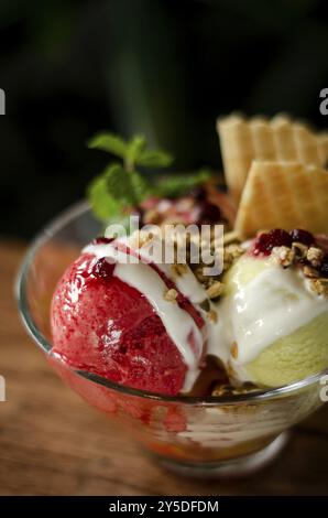 Crème glacée sundae à la fraise et à la pistache dans un bol sur une table en bois Banque D'Images