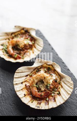 Cuisine gastronomique aux crevettes royales cuites dans une sauce épicée aux tomates et aux herbes Banque D'Images