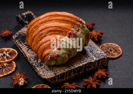 Croissant rouge sucré croustillant à la pistache, à la framboise et à la fraise sur un fond de béton foncé Banque D'Images