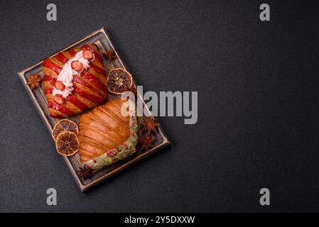 Croissant rouge sucré croustillant à la pistache, à la framboise et à la fraise sur un fond de béton foncé Banque D'Images