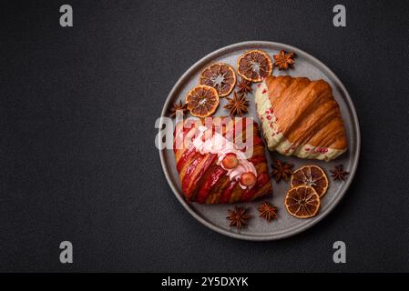 Croissant rouge sucré croustillant à la pistache, à la framboise et à la fraise sur un fond de béton foncé Banque D'Images