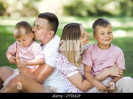 Livraison de baiser pour papa et maman. Photo recadrée d'une jeune famille passant du temps ensemble à l'extérieur. Banque D'Images