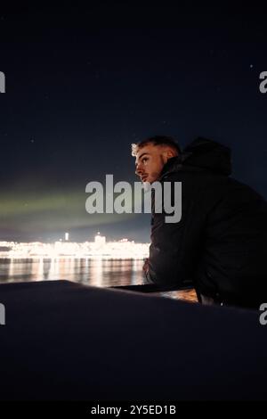 Homme sur une croisière dans le fjord sous les aurores boréales à Tromso, Norvège Banque D'Images