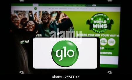 Dans cette illustration photo, une personne tient un téléphone portable avec le logo de la société de télécommunications nigériane Globacom Limited (GLO) devant la page Web. Banque D'Images