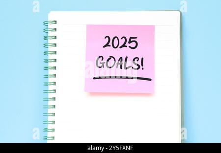 2025 objectifs écriture dans un cahier isolé sur fond bleu. Concept du nouvel an avec typographie 2025. Mots de motivation pour accueillir la nouvelle année 2025 Banque D'Images